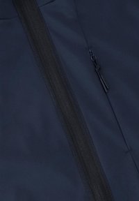 Detailní záběr na tmavě modrou látku s černým zipem a černým táhlem zipu připojeným pomocí smyčkového šňůrky.