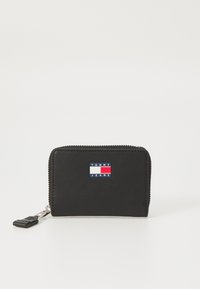 Svart lærplånbok med glidelås, med en fargeblokkert logo lapp i blått, rødt og hvitt foran. Kompakt design, glatt tekstur.
