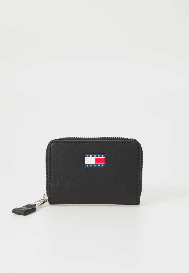 Μαύρο δερμάτινο πορτοφόλι με φερμουάρ, με λογότυπο σε μπλε, κόκκινο και λευκό χρώμα στο μπροστινό μέρος. Συμπαγής σχεδίαση, λείος υφή.