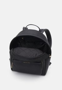 Zaino in pelle nera con una finitura testurizzata, interni in tessuto nero trapuntato e dettagli in hardware dorato. Presenta una maniglia superiore e spallacci regolabili.