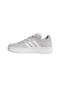 Baskets basses Adidas gris et blanc avec lacets, trois bandes blanches sur le côté et une semelle blanche épaisse sur fond blanc.