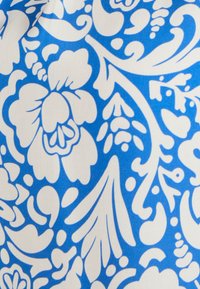 Tessuto floreale blu e bianco con grandi fiori e intricate spirali, con una texture liscia e un vivace contrasto di colori.
