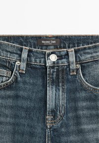 Dark blue denim jeans with a classic five-pocket design, contrasting orange stitching, a metal button, and a label reading "Massimo Dutti."