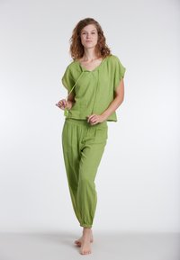 Completo in cotone leggero verde, composto da una maglietta a maniche corte con scollo a giro e cordoncino, abbinato a pantaloni a sigaretta.