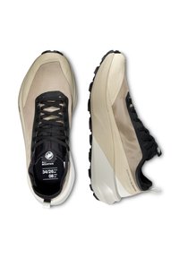 Μπεζ και μαύρα παπούτσια για τρέξιμο σε μονοπάτια με παχιά σόλα, μαύρα κορδόνια και σήμανση "All Mountain" στο εσωτερικό και στην πλευρά.