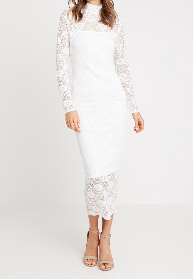 Weißes Spitzenkleid mit langen Ärmeln, figurbetontem Design und Blumenmustern. Midi-Länge mit gewelltem Saum. Getragen mit beigen Riemchen-Absätzen.