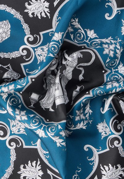 Material albastru și negru cu figuri florale albe detaliate și figuri clasice în modele ornamentale și simetrice, prezentând pliuri și textură.