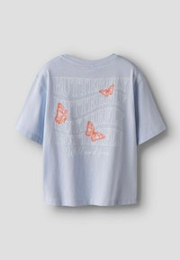 Camiseta de algodón de color azul claro con mangas cortas y un diseño recortado. Presenta el texto "BUTTERFLY" y ilustraciones de mariposas naranjas en la parte posterior.