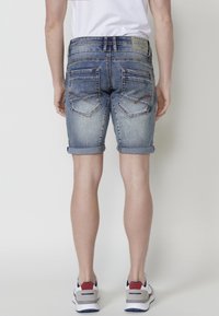 Denim kratke hlače u svijetloplavom pranju s uvijenim rubovima, s dva stražnja džepa sa zakrivljenim šavovima. Jednostavan i ležeran dizajn.