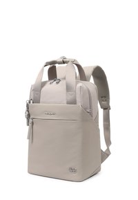 Sac à dos compact beige avec double poignées supérieures, bretelles rembourrées, poche avant zippée et logos métalliques de la marque sur tissu lisse.