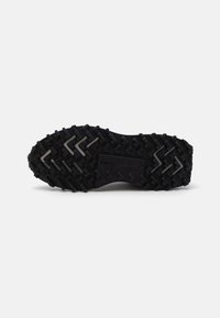 Black rubber sneaker sole with a textured zigzag pattern and small lugs for grip. Features a debossed logo near the arch area.