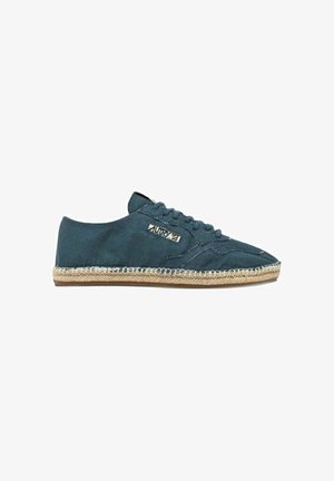 Scarpa da ginnastica in tela blu scuro con lacci, suola in espadrillas beige cucita e piccola etichetta rettangolare del marchio sul lato.
