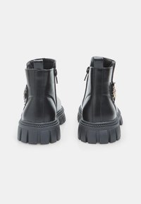 Botas negras de cuero hasta el tobillo con suela gruesa, que cuentan con cremalleras laterales, detalles texturizados y costuras reforzadas a lo largo de los bordes.