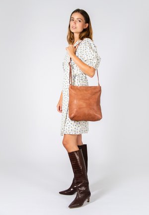 Borsa a spalla in pelle marrone chiaro con una texture liscia e un design minimalista. La borsa presenta una lunga tracolla e una forma morbida e non strutturata.
