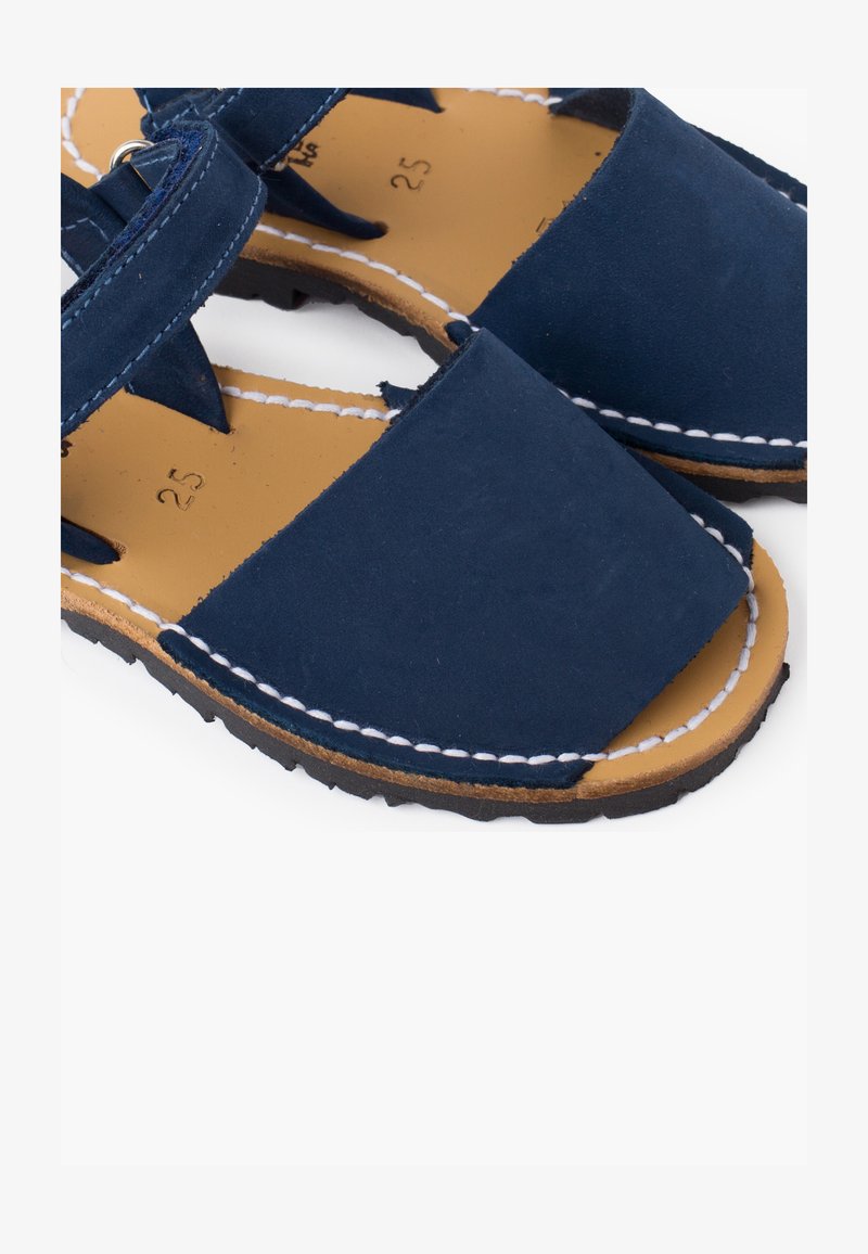 Navy blue sandals with a smooth leather upper, square toe, and white stitching on a tan insole. Features a sturdy black rubber outsole.