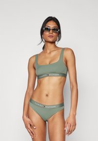 Olive zelený, bezšvový set braletky a bikiny s logem na pásu. Materiál vypadá hladce a elasticky, s designem čtvercového výstřihu.