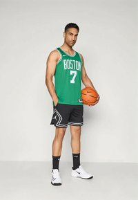 Zaļš basketbola krekls ar uzrakstu "BOSTON" un numuru 7; melnas šortus ar baltām akcentiem; tur oranžā basketbola bumbiņa; kājās balti kedas.