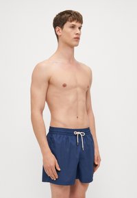 Navyblaue Badeshorts mit elastischem Bund, Kordelzug und Seitentaschen. Glattes, leichtes Material. Auffälliges, sauberes Design.
