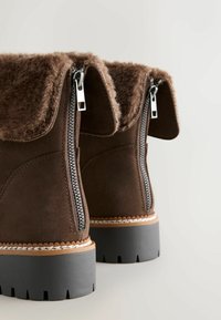 Pruunid nahast pahkluu saapad vale fliisvoodriga, kahekordsete külgzipritega, musta kummitaldaga ja äärise ääristamisega.