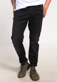 Svarta jeans i denim med slim fit, med en medelhög midja, framfickor och en mjuk textur. I kombination med olivgröna sportskor.