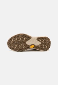 Vibram outsole featuring a brown rubber base with a zigzag tread pattern. The center has a yellow Vibram logo and a textured design.