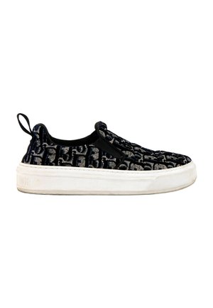 Baskets noires sans lacets avec semelle blanche et motif monogramme texturé, avec une languette en tissu au talon.