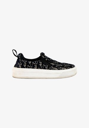 Baskets noires sans lacets avec semelle blanche et motif monogramme texturé, avec une languette en tissu au talon.