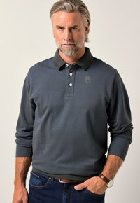 Poloko s dlouhým rukávem v tmavě modré barvě s černým límečkem, tříknoflíkovou légou, texturovanou tkaninou a jemným logem na oblasti hrudi.