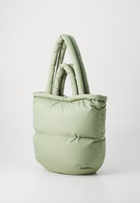 Sac fourre-tout rembourré en vert clair, avec deux poignées rondes et une silhouette structurée et douce avec une texture matelassée.
