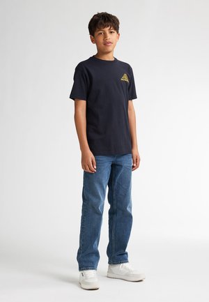 Marineblauwe katoenen T-shirt met een ronde hals en een gele bedrukte grafiek; gecombineerd met lichtblauwe jeans en witte sneakers.