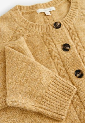 Sweter kardigan w miękkim złotym odcieniu żółtego z wzorami warkoczowymi, z posiadającymi żeberkowe ściągacze mankietami oraz dwoma ciemnobrązowymi guzikami z przodu.