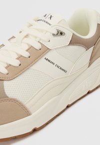 Tenisi bej și crem, cu un superior din plasă texturată, accente din piele netedă, talpă cu pernițe și branding "Armani Exchange".