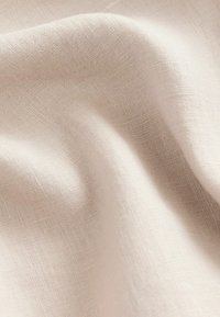 Tăbăcarie bej deschis, cu o textură moale și o țesătură fină, având un luciu ușor și pliuri naturale, ideală pentru diverse aplicații textile.