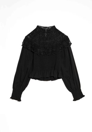 Blouse noire avec un col montant large bordé de dentelle, des poignets élastiqués et un ourlet à volants, avec un corps smocké pour une silhouette ajustée.