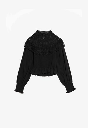 Blouse noire avec un col montant large bordé de dentelle, des poignets élastiqués et un ourlet à volants, avec un corps smocké pour une silhouette ajustée.