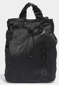 Black canvas bag with gathered top, drawstring closure, and shiny printed logo. Offers a textured finish and minimalist design.
