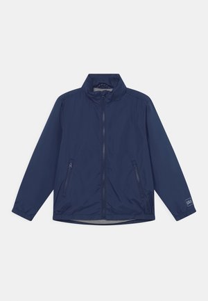 Giacca windbreaker blu navy con colletto alto, zip completa e due tasche laterali con zip. Realizzata in tessuto leggero e liscio.