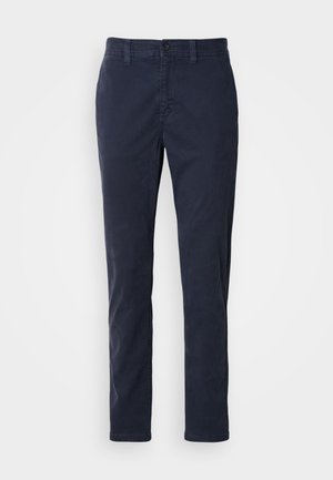 Marineblå slim-fit bomuldsbukser med bæltestropper og knaplukning, vist på en hvid baggrund.
