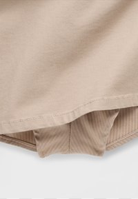 Beiger Baumwollstoff mit Fischgrätmuster, verziert mit einem gesäumten Rand und sichtbaren Nähten. Glatte Textur mit lockerem Sitz.