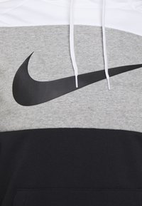 Sweat à capuche Nike avec capuche blanche, milieu gris et bas noir. Grand logo Swoosh noir sur la poitrine, texture de tissu douce.