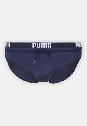 Mornarske plave gaće u tamnoplavoj boji od rastezljivog materijala s PUMA logom na pojasu, s vezicom za prilagodljivo pristajanje.