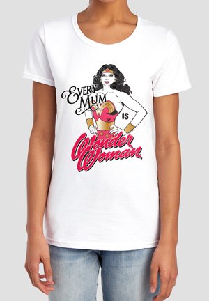 White t-shirt with vintage Wonder Woman graphic and text "Every Mum is Wonder Woman" worn by person in blue jeans.