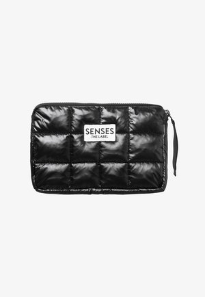 Black quilted pouch made of shiny material, featuring a zip closure and a label with "SENSES .THE LABEL" in white. Textured pattern.