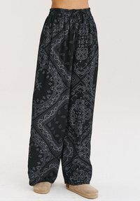 Czarne spodnie szerokie w nogawkach z białym wzorem paisley. Wykonane z lekkiego materiału, z elastycznym pasem i sznurkiem do regulacji.