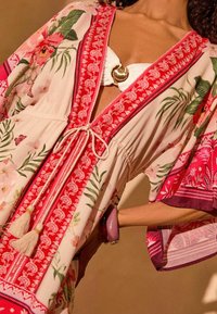 Floral kimono stil pokrivač s crvenim i ružičastim akcentima, s prednjim vezanjem, detaljima resica i širokim rukavima. Lagana tkanina.