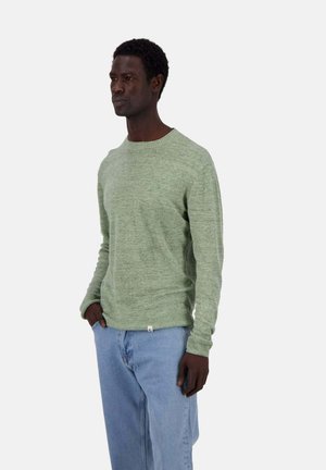 Hellgrüner gestrickter Pullover mit Rundhalsausschnitt und langen Ärmeln, ausgestattet mit einem strukturierten Stoff und gerippten Bündchen, kombiniert mit blauen Jeans.