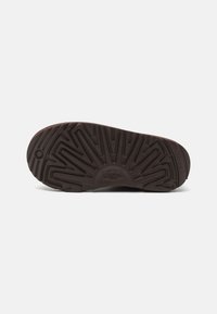 Talpa de cauciuc maro cu un model texturat în zigzag și logo ridicat. Prezintă striații adânci pentru aderență și stabilitate.