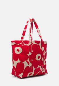 Sac fourre-tout rouge avec de grands motifs floraux rouge et crème, fabriqué en tissu durable, doté de deux poignées et d'une base plate.