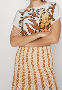 Robe à manches courtes avec un haut blanc à motif léopard orange et une jupe fluide à rayures orange et blanches.