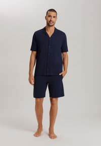 Donkerblauwe shirt met korte mouwen en bijpassende shorts, gemaakt van zacht materiaal, met een knoopsluiting aan de voorkant en een ontspannen pasvorm. Geen opvallende patronen.